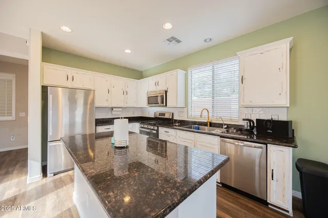 a kitchen with stainless steel appliances granite countertop a sink a stove and refrigerator