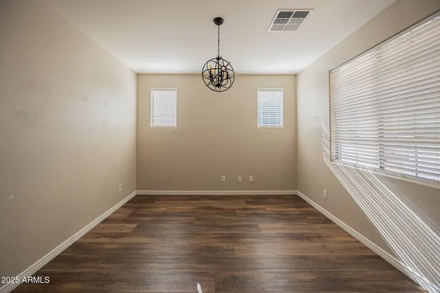 a view of an empty room with wooden floor and windows