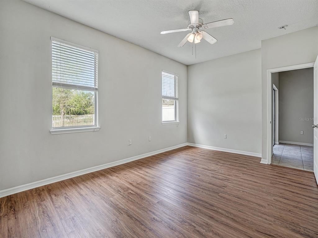 11713 Colony Lakes Boulevard New Port Richey, FL 34654 - Photo 17 of 38 an empty room with wooden floor chandelier fan and windows