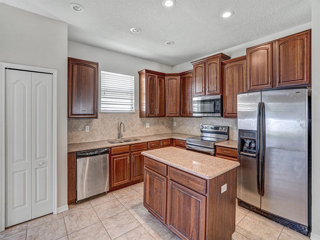 11713 Colony Lakes Boulevard New Port Richey, FL 34654 - Photo 8 of 38 a kitchen with stainless steel appliances granite countertop a stove a sink dishwasher and a refrigerator