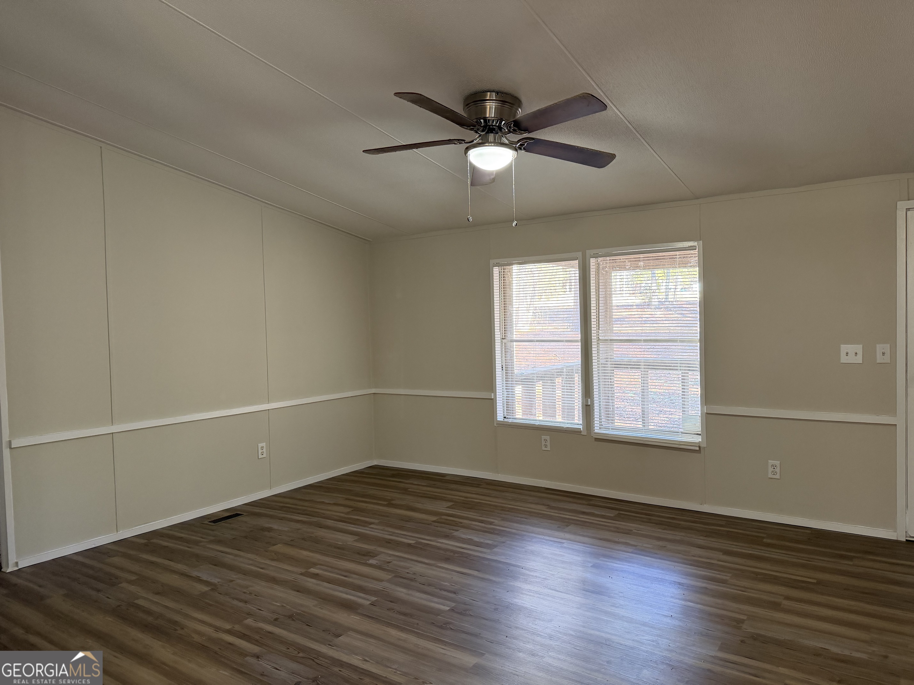 927 Louis Road Rentz, GA 31075 - Photo 8 of 22 an empty room with wooden floor fan and windows