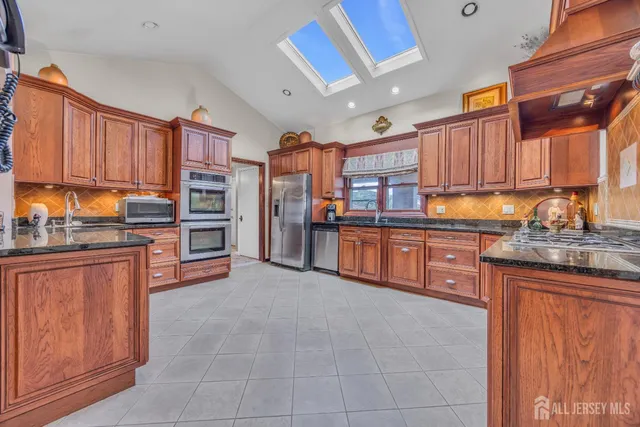 a kitchen with stainless steel appliances granite countertop a refrigerator and wooden cabinets