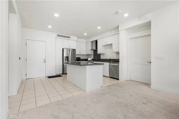 a kitchen with granite countertop a refrigerator a sink and white cabinets