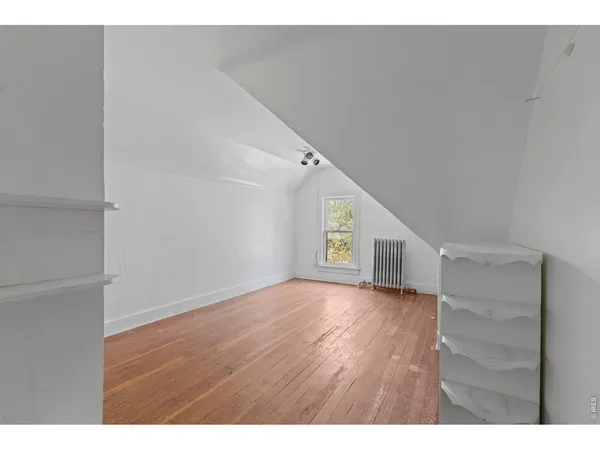 a view of an empty room with wooden floor and closet