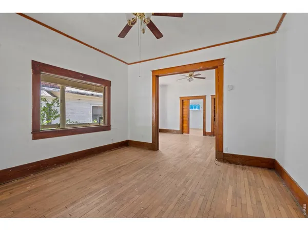 a view of an empty room with wooden floor and a window