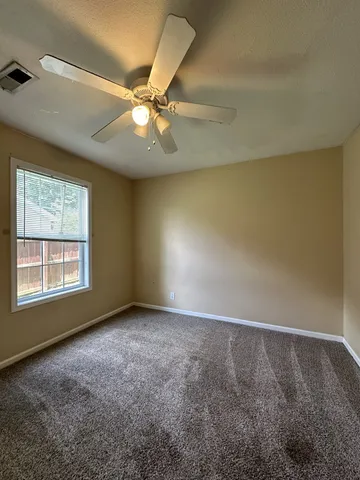 an empty room with a window and a fan
