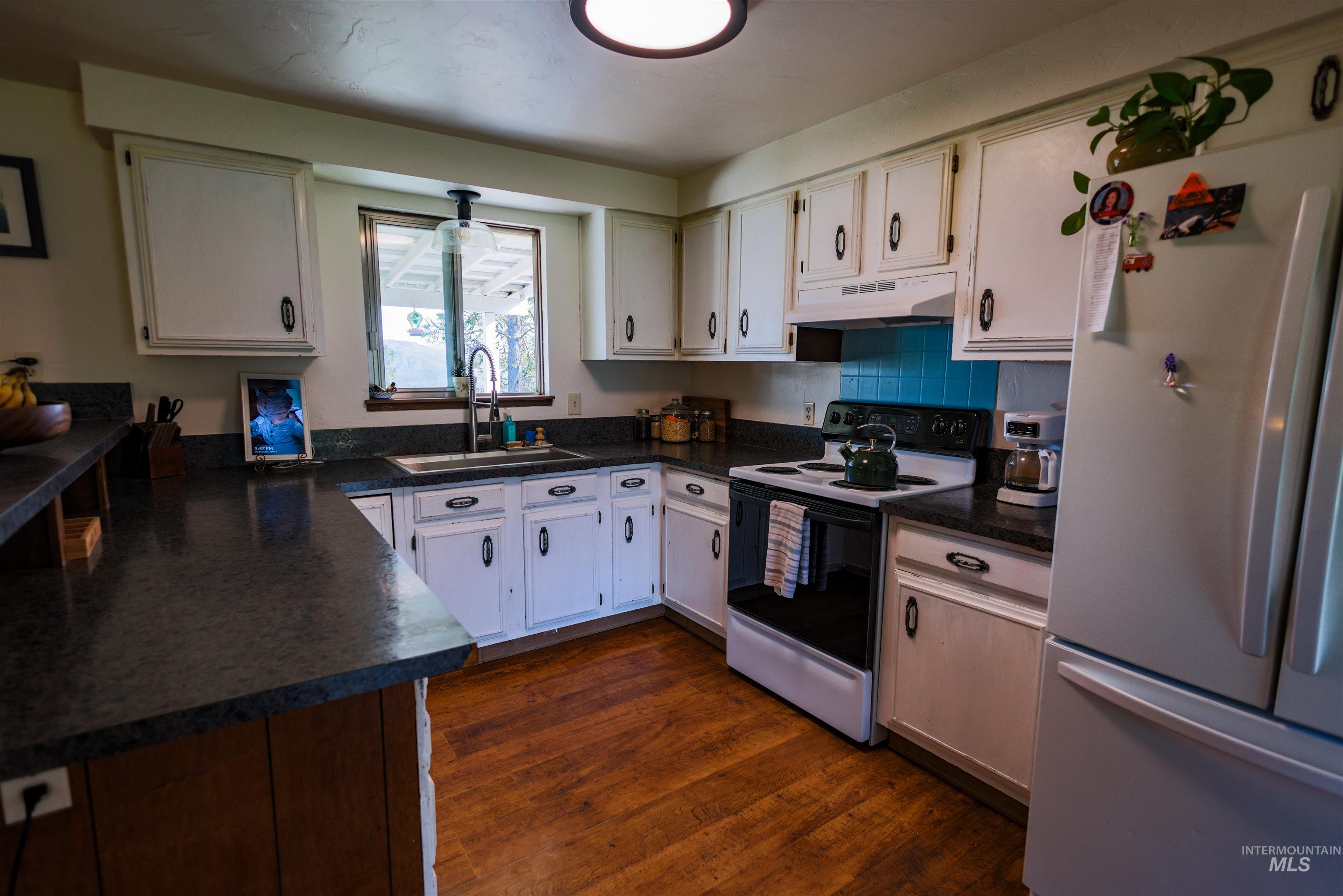 3230 Highway 64 Kamiah, ID 83536 - Photo 33 of 50 Kitchen with dark countertops, freestanding refrigerator, range with electric stovetop, white cabinets, and tasteful backsplash