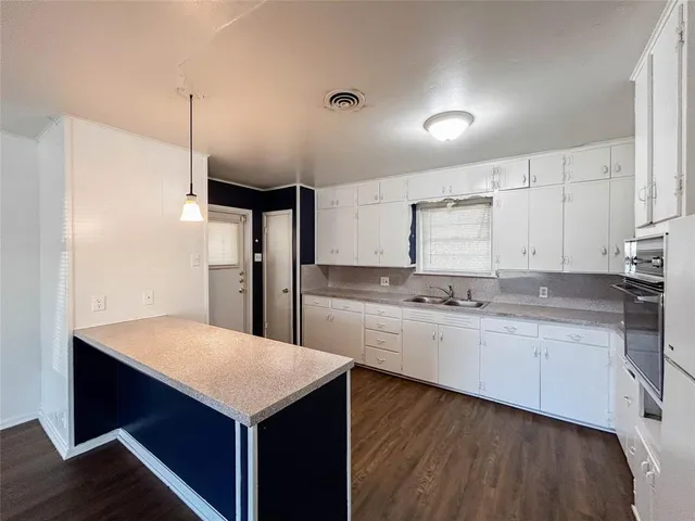 a kitchen with a sink a refrigerator and white cabinets
