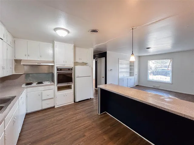 a kitchen with stainless steel appliances kitchen island granite countertop a stove a sink and white cabinets