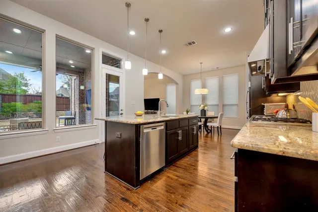 a kitchen with stainless steel appliances granite countertop wooden cabinets a sink a stove and a refrigerator