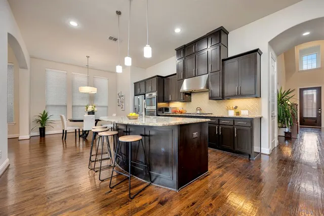 a kitchen with stainless steel appliances kitchen island granite countertop wooden floors and view living room