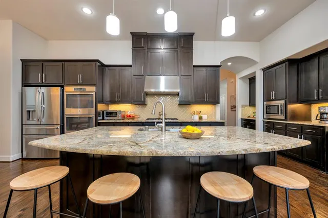 a kitchen with stainless steel appliances granite countertop a table chairs stove refrigerator and microwave