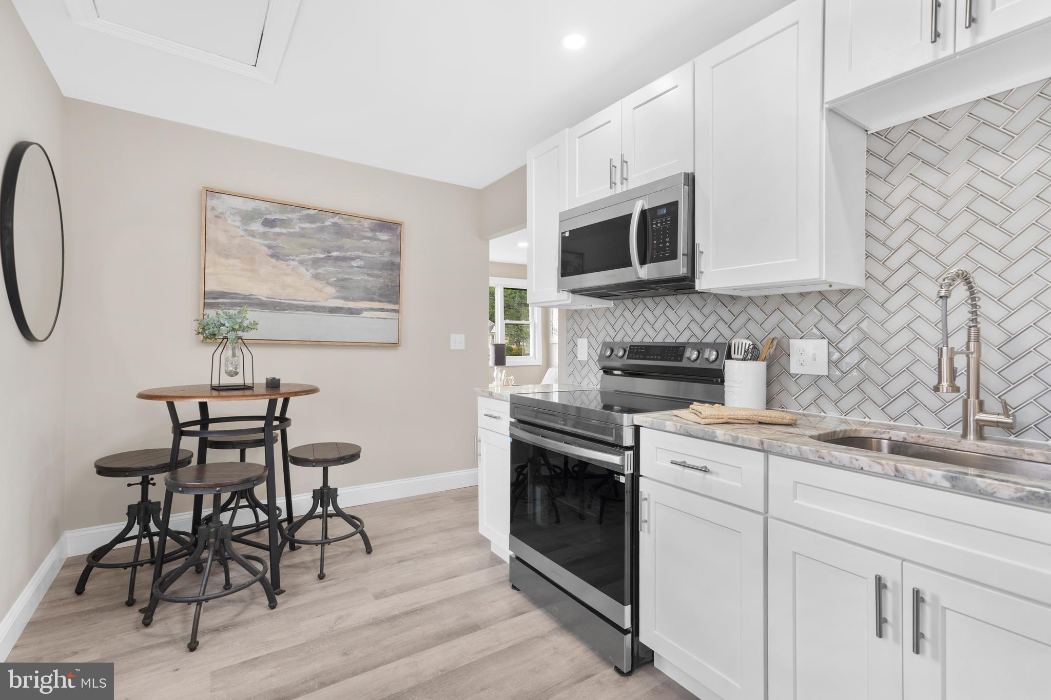 1 Gainor Avenue Maple Shade, NJ 08052 - Photo 5 of 27 a kitchen with stainless steel appliances granite countertop a stove top oven a sink a dining table and chairs with wooden floor