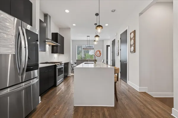 a large kitchen with stainless steel appliances granite countertop a refrigerator a stove top oven a sink dishwasher and wooden floor