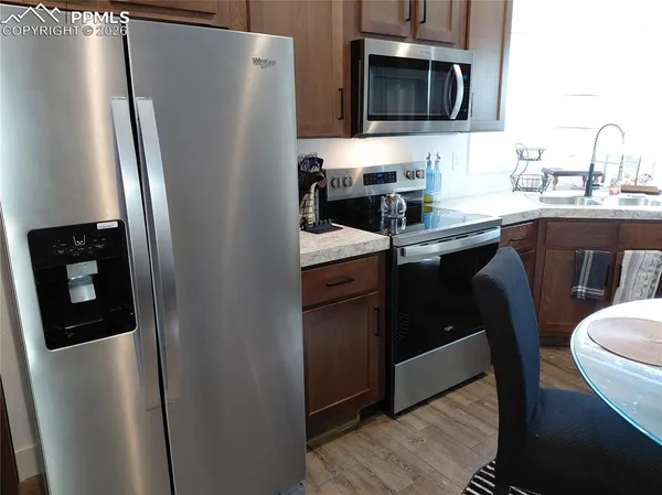 a kitchen with stainless steel appliances granite countertop a refrigerator a sink a stove a microwave and wooden cabinets