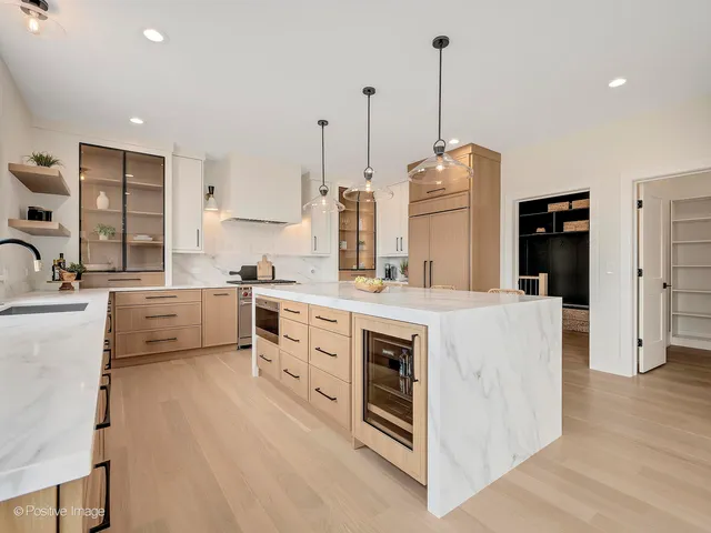 a kitchen that has a lot of white cabinets and stainless steel appliances