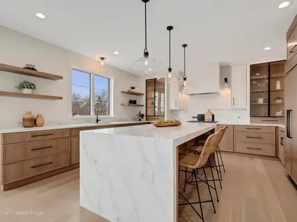 a kitchen with stainless steel appliances kitchen island granite countertop a table chairs in it and white cabinets