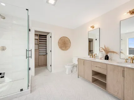 a spacious bathroom with a double vanity sink a toilet and a shower