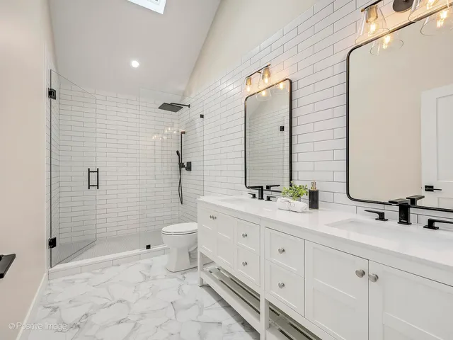 a bathroom with a double vanity sink toilet and shower