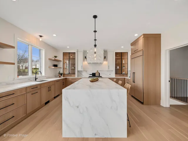 a large white kitchen with granite countertop a stove a sink dishwasher and a refrigerator with wooden floor