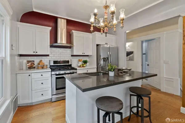 a kitchen with stainless steel appliances granite countertop a stove top oven a sink dishwasher and white cabinets with wooden floor