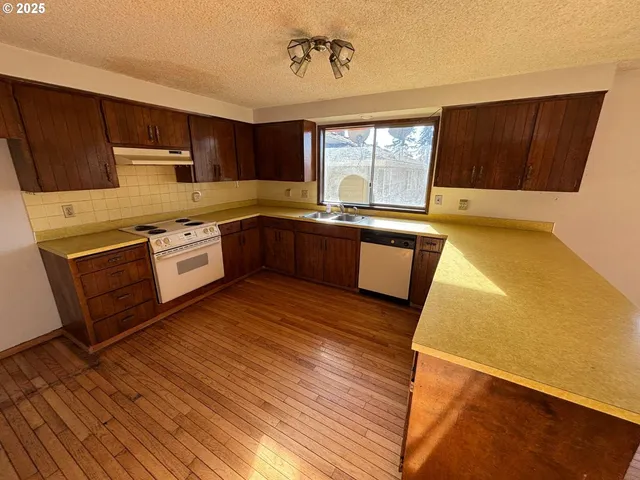 a large kitchen with stainless steel appliances granite countertop a stove a sink dishwasher and wooden cabinets with wooden floor