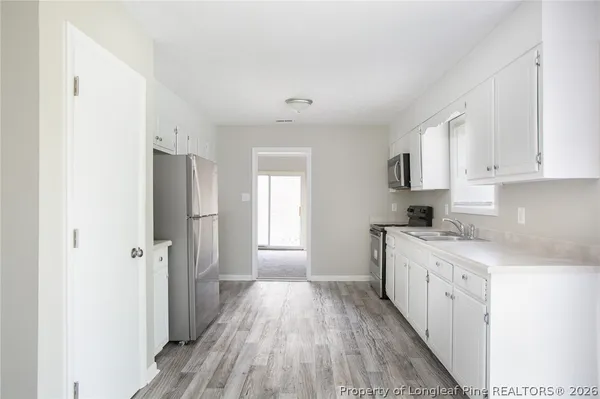 a kitchen with a refrigerator a sink and dishwasher with wooden floor