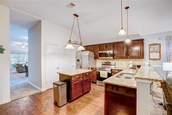 a open kitchen with stainless steel appliances kitchen island granite countertop a sink a stove and a wooden floor