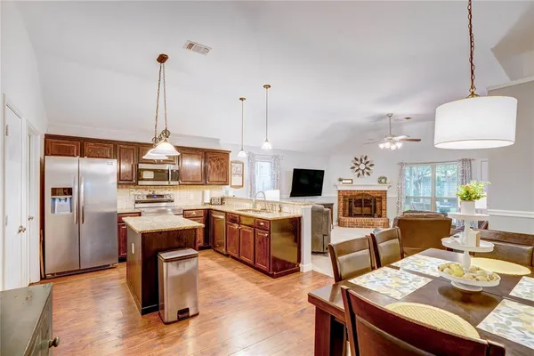 a view of a dining room and livingroom with furniture wooden floor a rug a fireplace and a chandelier