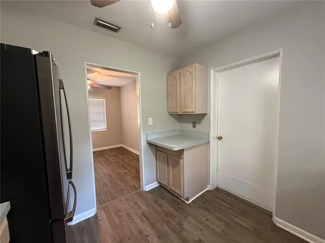 an empty room with wooden floor chandelier fan and windows