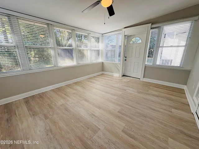 a view of an empty room with a window and wooden floor