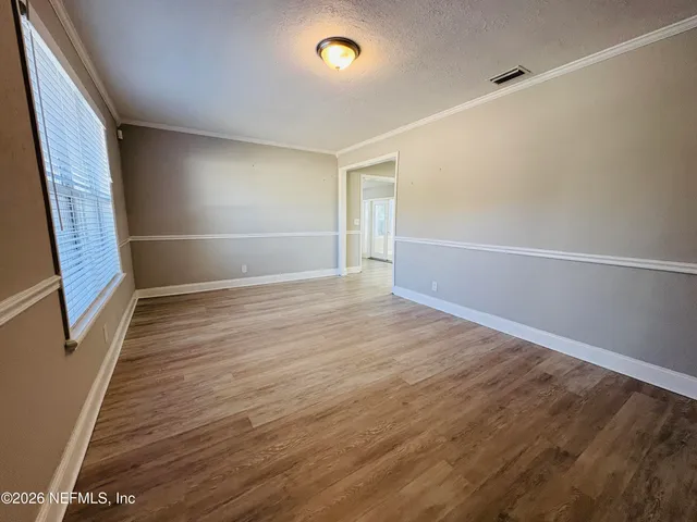 a view of an empty room with wooden floor and a window