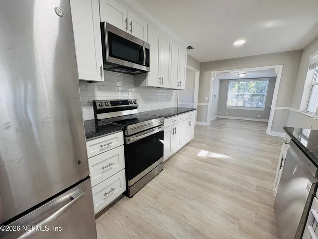 a kitchen with stainless steel appliances granite countertop a stove a microwave and a refrigerator