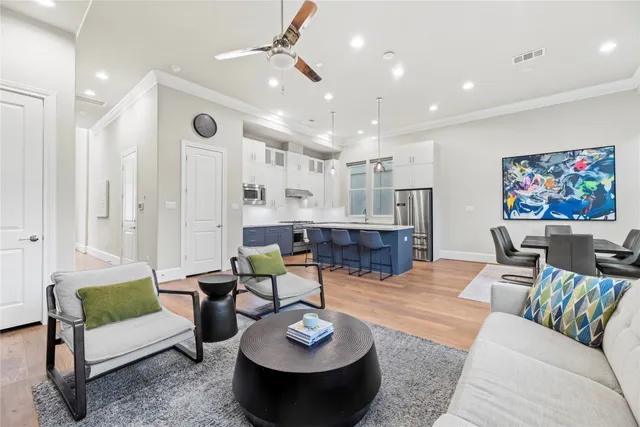 a kitchen with stainless steel appliances granite countertop a sink a stove a dining table and chairs with wooden floor