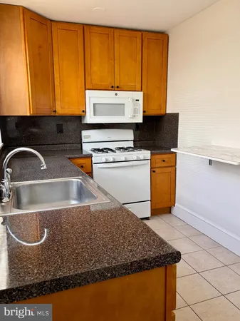 a kitchen with kitchen island a sink a stove and a microwave oven in a shelf
