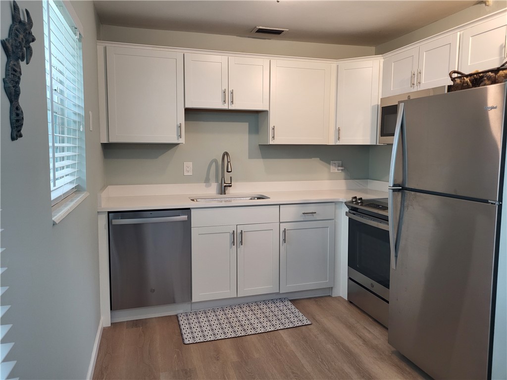a kitchen with a sink dishwasher a refrigerator and cabinets