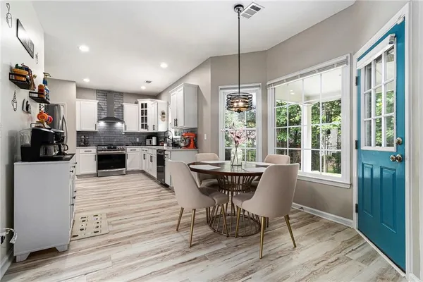 a kitchen with stainless steel appliances granite countertop a stove a refrigerator a sink dishwasher a dining table and chairs with wooden floor
