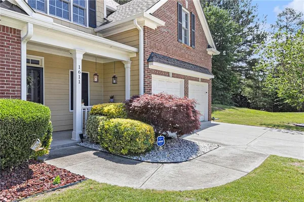 a view of a house with brick walls plants and large tree