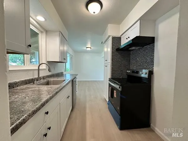 a kitchen with granite countertop a sink and a stove top oven