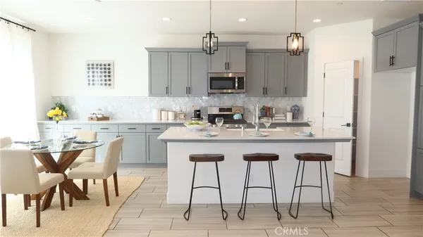 a kitchen with stainless steel appliances kitchen island granite countertop a sink a stove a dining table and chairs