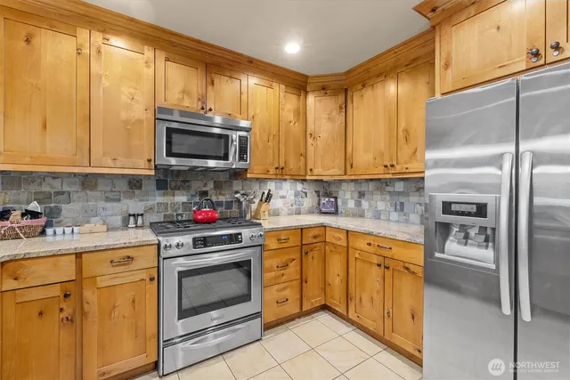 a kitchen with stainless steel appliances granite countertop a stove a sink and a microwave