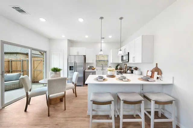 a dining room with stainless steel appliances kitchen island granite countertop a dining table chairs and view living room