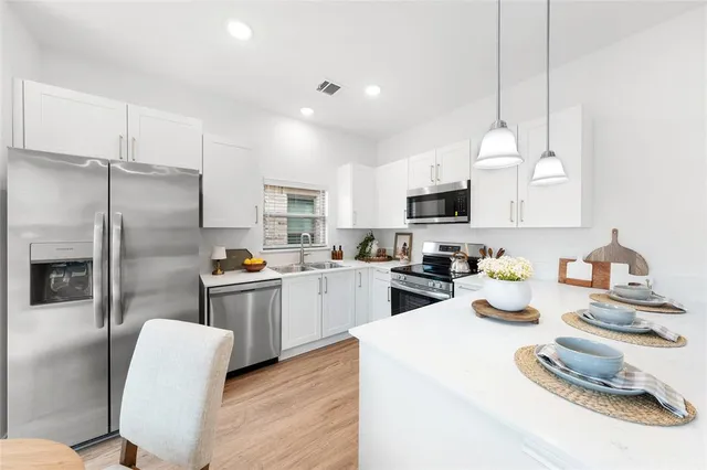 a kitchen with stainless steel appliances granite countertop a refrigerator a stove a sink dishwasher a oven with white cabinets and wooden floor