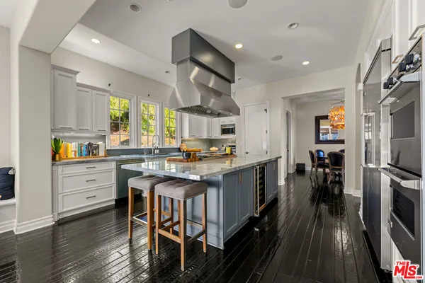 a kitchen with stainless steel appliances kitchen island granite countertop a table chairs refrigerator and sink