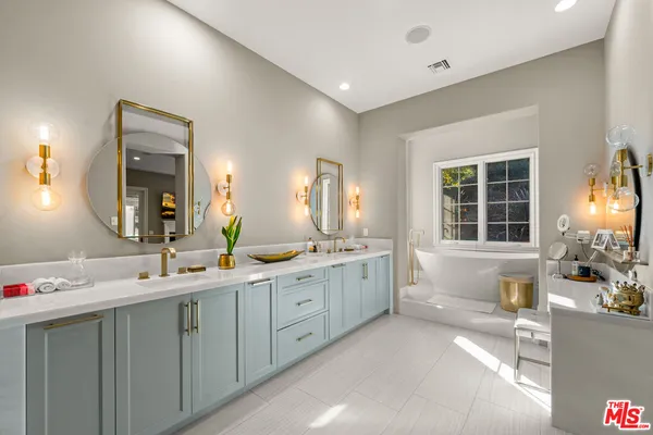a spacious bathroom with a double vanity sink large mirror and a bathtub