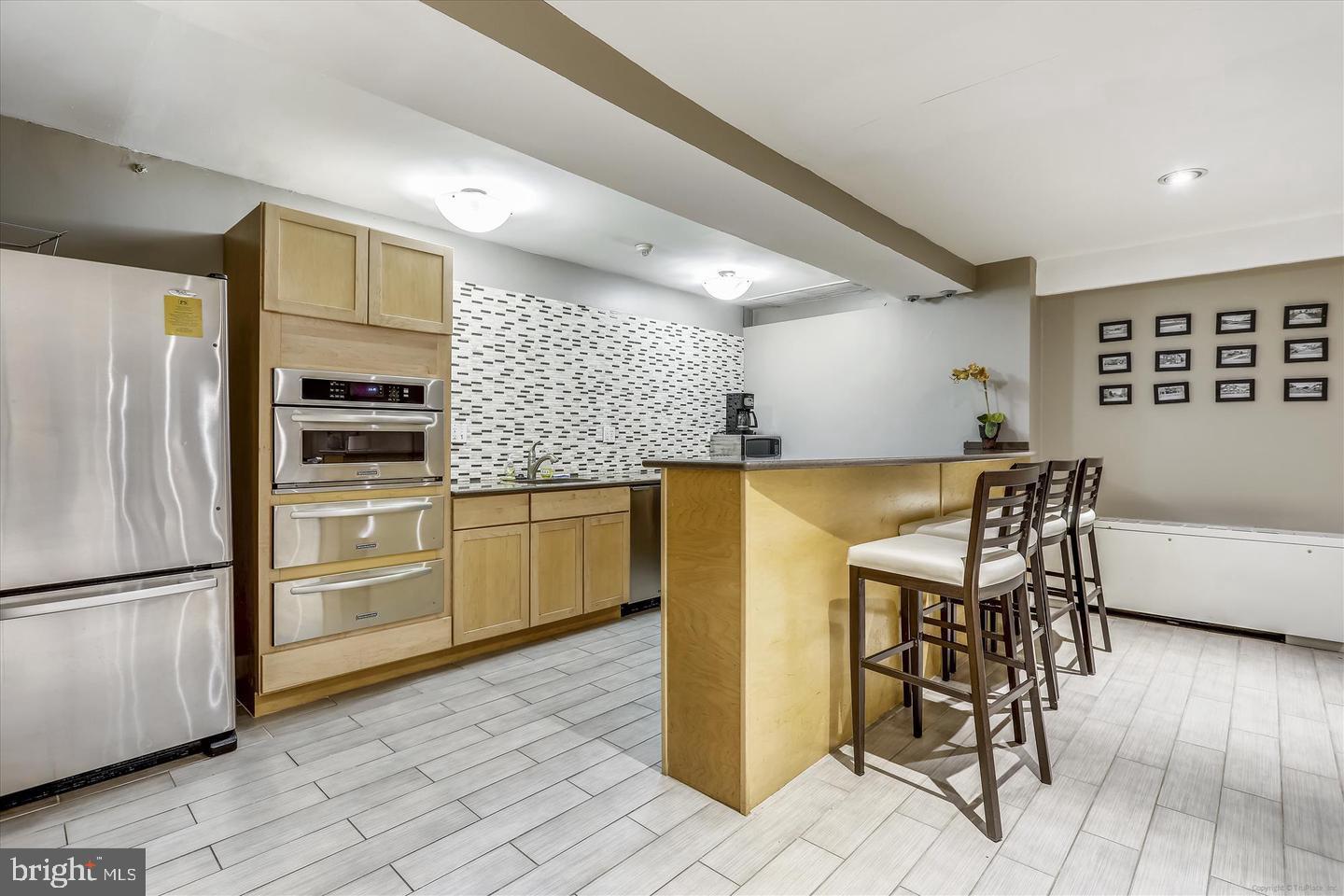 1900 Lyttonsville Road, Unit 602 Silver Spring, MD 20910 - Photo 31 of 43 a kitchen with granite countertop a refrigerator a stove a dining table and chairs with wooden floor