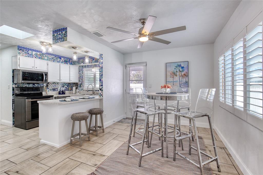1127 Indigo Road Ormond Beach, FL 32174 - Photo 16 of 94 a dining room with wooden floor a chandelier fan a glass table and chairs