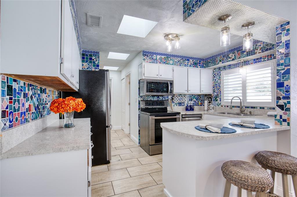 1127 Indigo Road Ormond Beach, FL 32174 - Photo 17 of 94 a kitchen with stainless steel appliances granite countertop a sink dishwasher stove a refrigerator and a dining table with the kitchen view