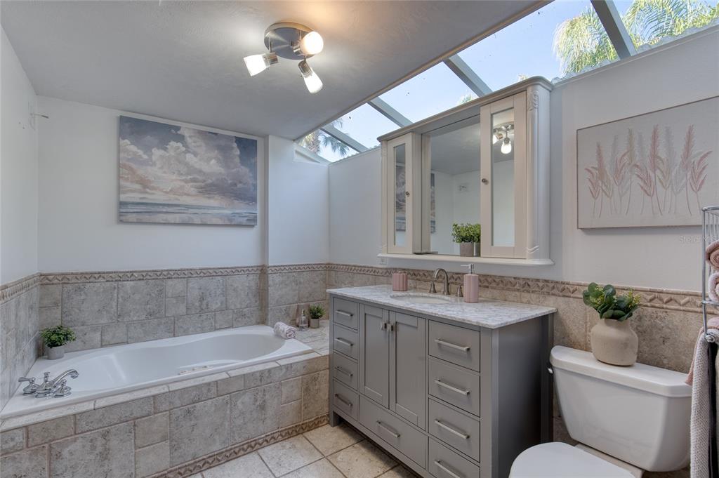 1127 Indigo Road Ormond Beach, FL 32174 - Photo 37 of 94 a bathroom with a granite countertop sink a large mirror a bathtub and a toilet