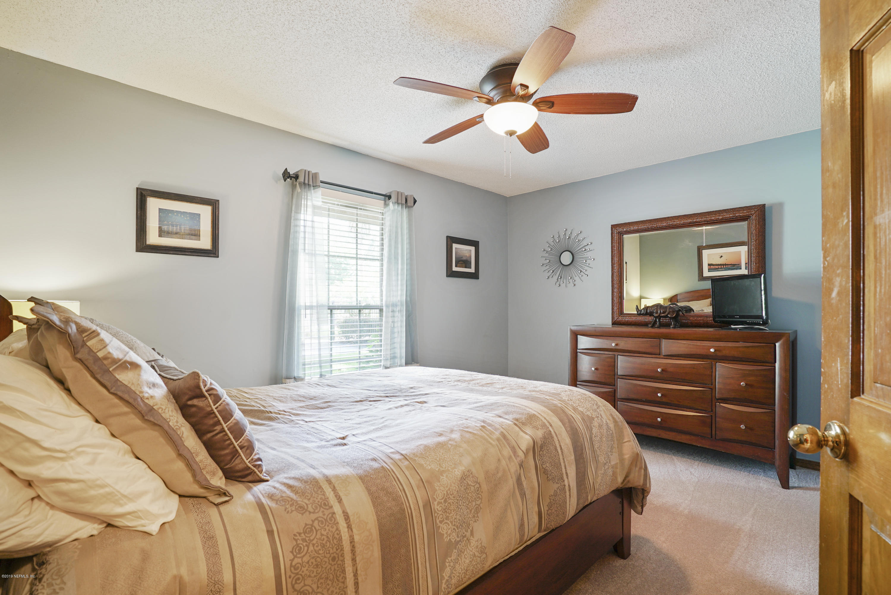 3165 Nautilus Road Middleburg, FL 32068 - Photo 19 of 35 a bedroom with a bed and a chandelier